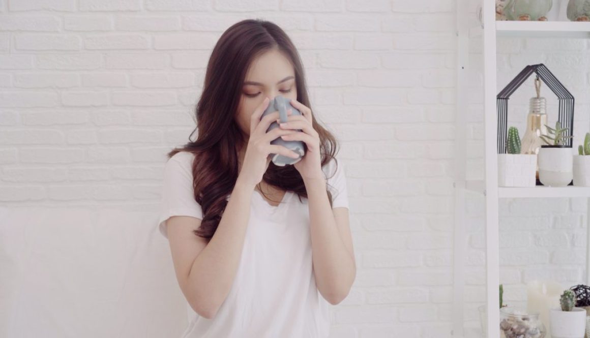 Happy beautiful Asian woman smiling and drinking a cup of coffee